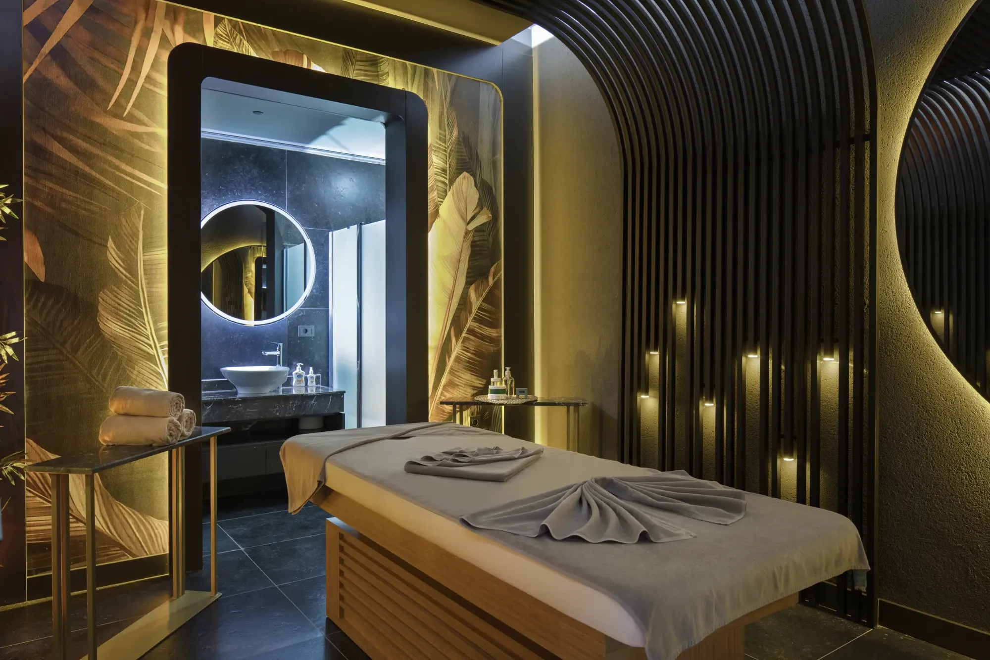 Mirage Park Spa masaj odası, tropikal yaprak desenli duvar ve loş ışıklar